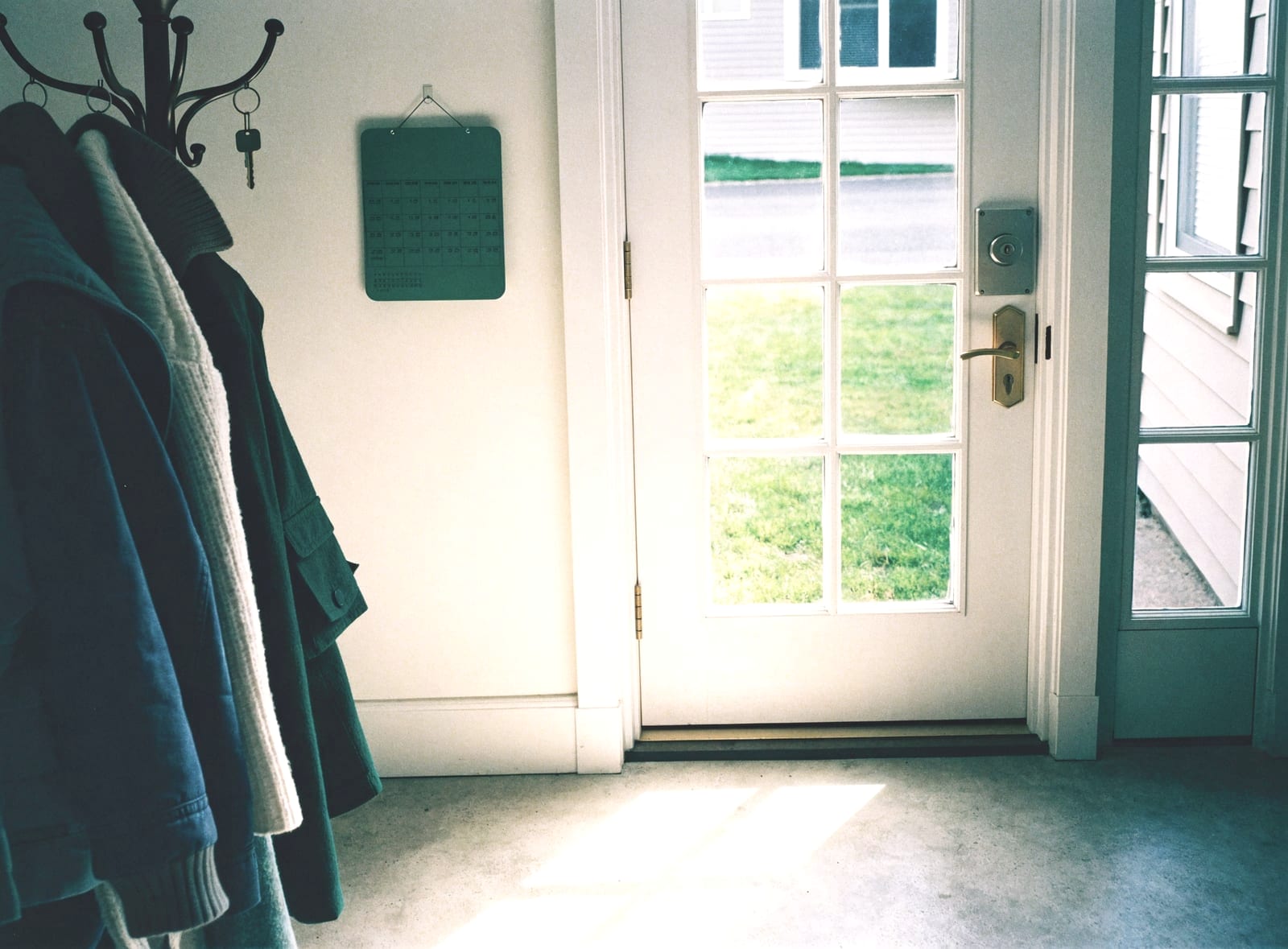 Entryway with coats on hooks beside a glass front door