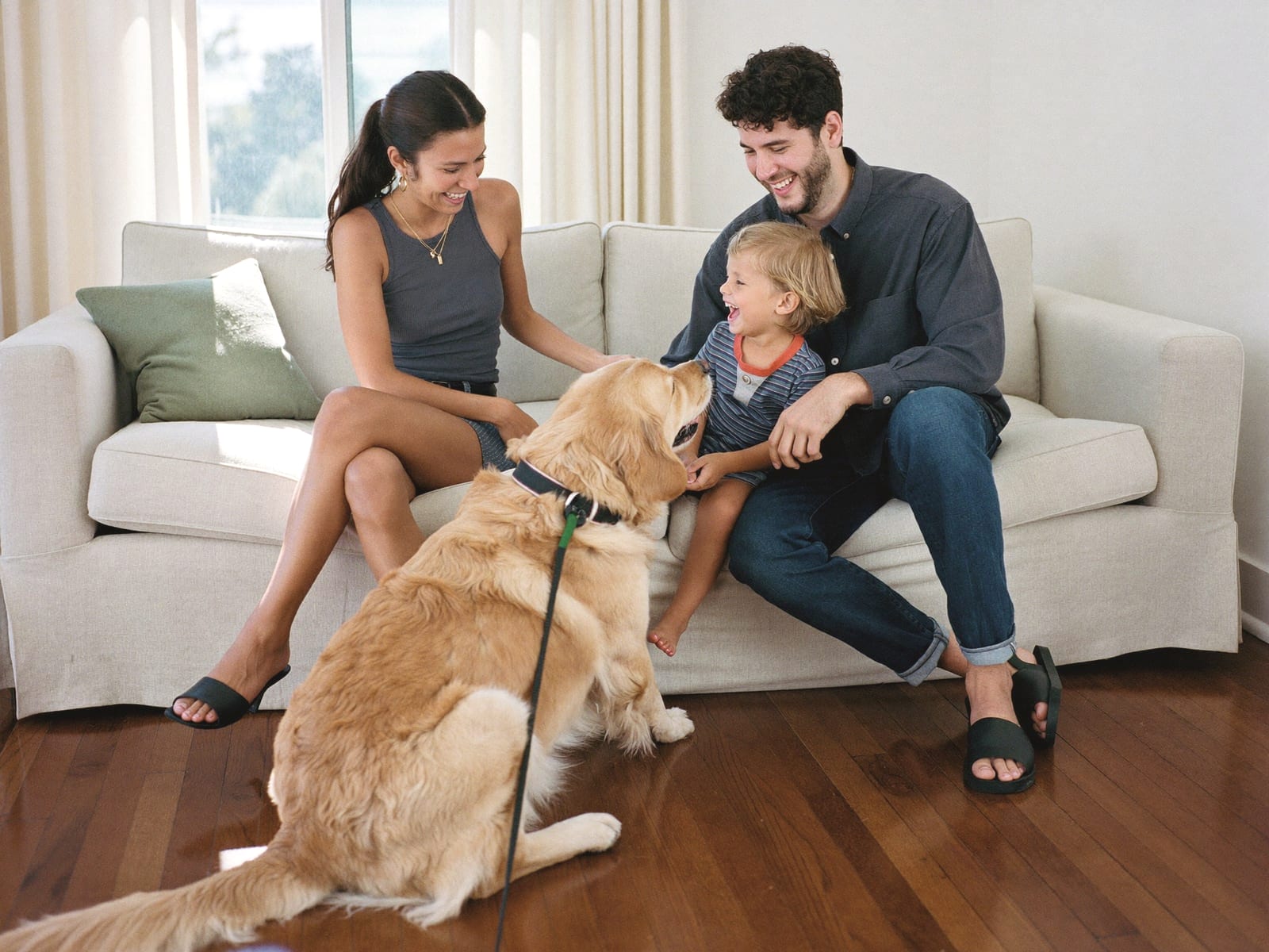 A family with their golden retriever relaxing on a sofa in a clean living room